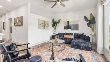 A modern living room with a sofa set, a coffee table, and a ceiling fan.