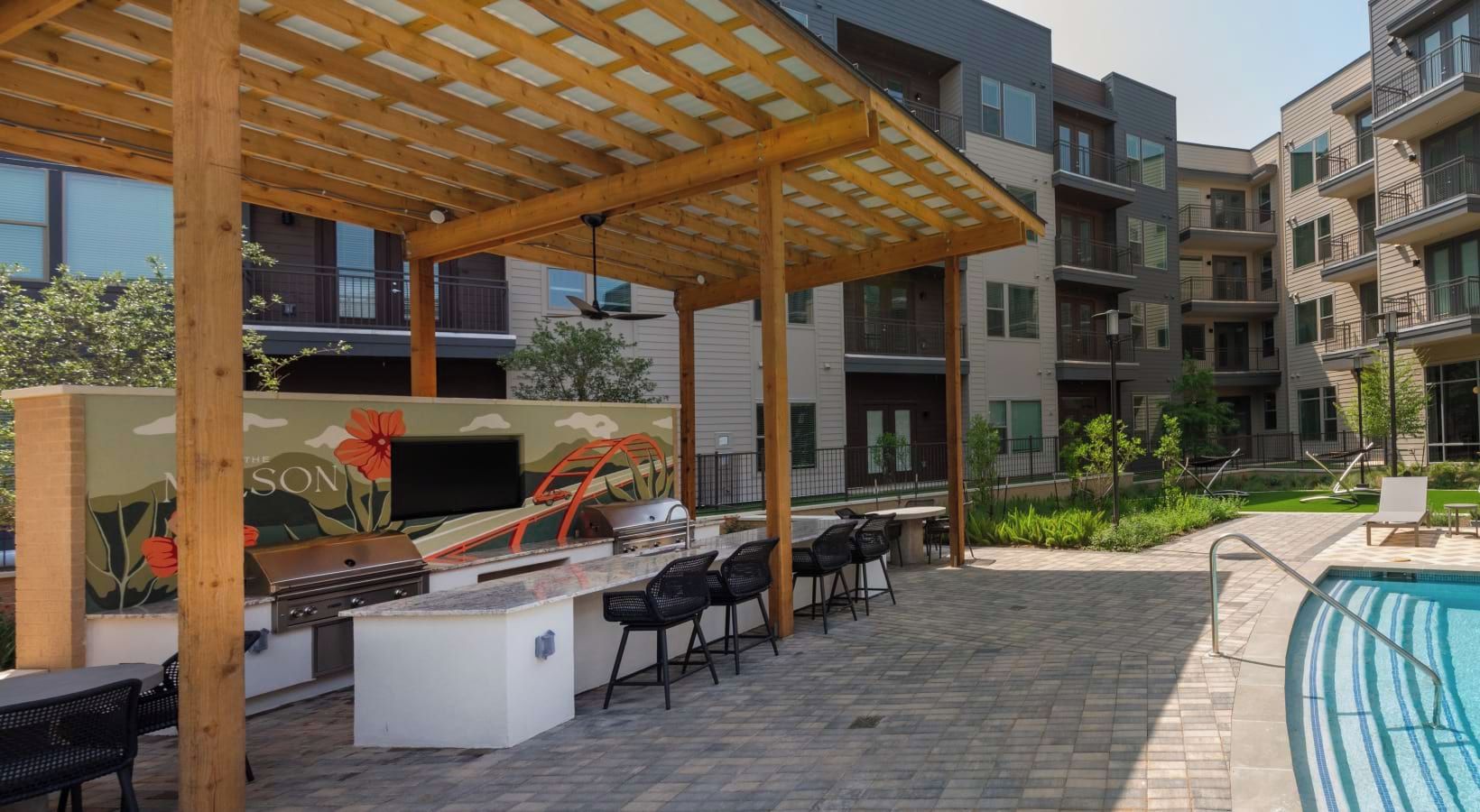 An outdoor patio with a barbecue area, seating, and a pool.