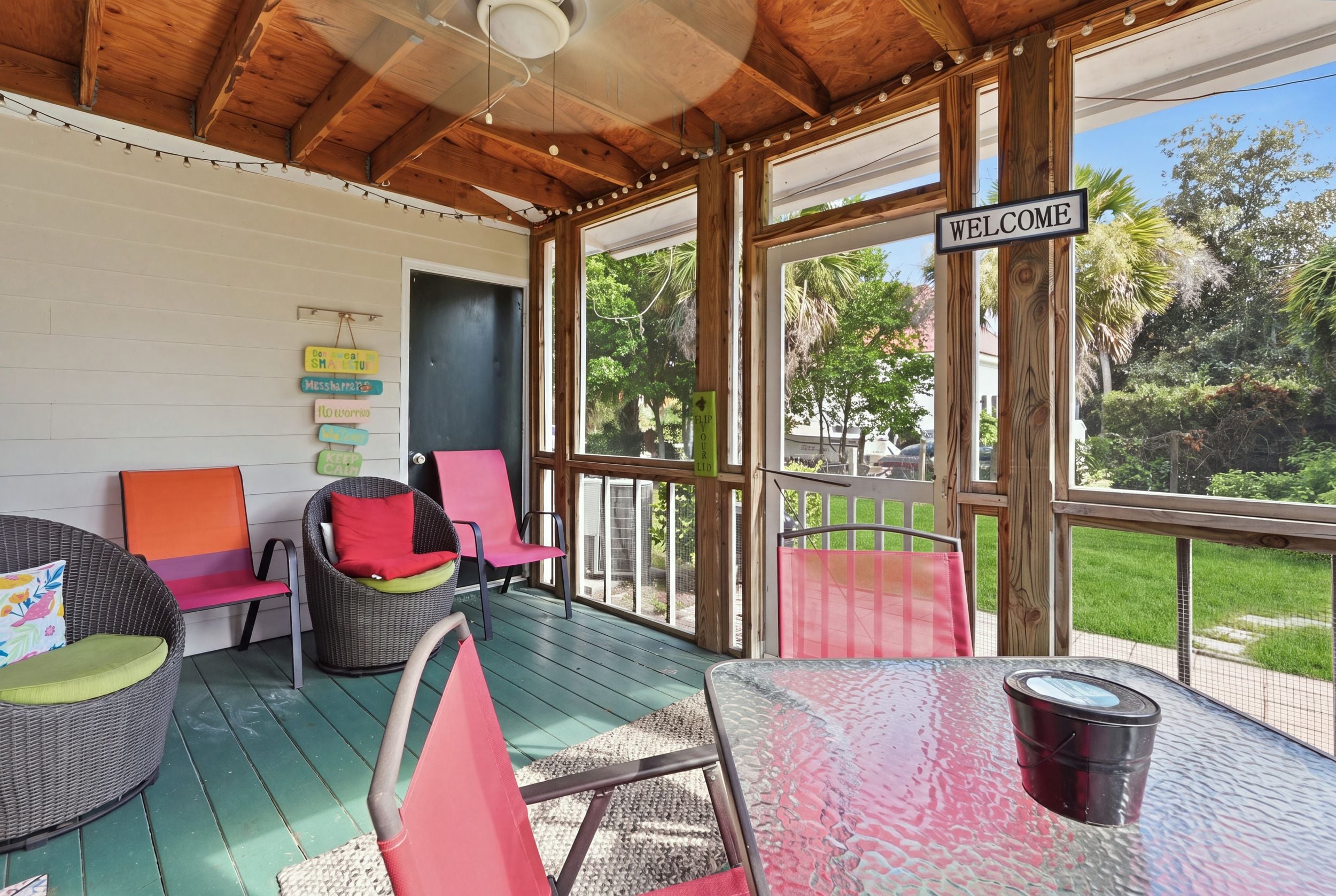 A covered porch with wicker furniture, a welcome sign, and a view of the outdoors.