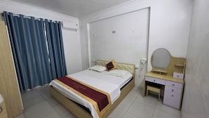 A hotel room with a bed, a bedside table with a mirror, a telephone, and a wardrobe. - Vĩnh Phát Hotel (Soc Son)