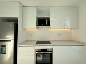 A modern kitchen with stainless steel appliances, including a refrigerator, microwave, and oven. - Luxurious and Bright 2-Bedroom, 2-Bathroom Home in Concepción Live (Buenos Aires)