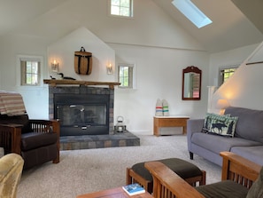 A cozy living room with a fireplace, wooden furniture, and a view of the outdoors.