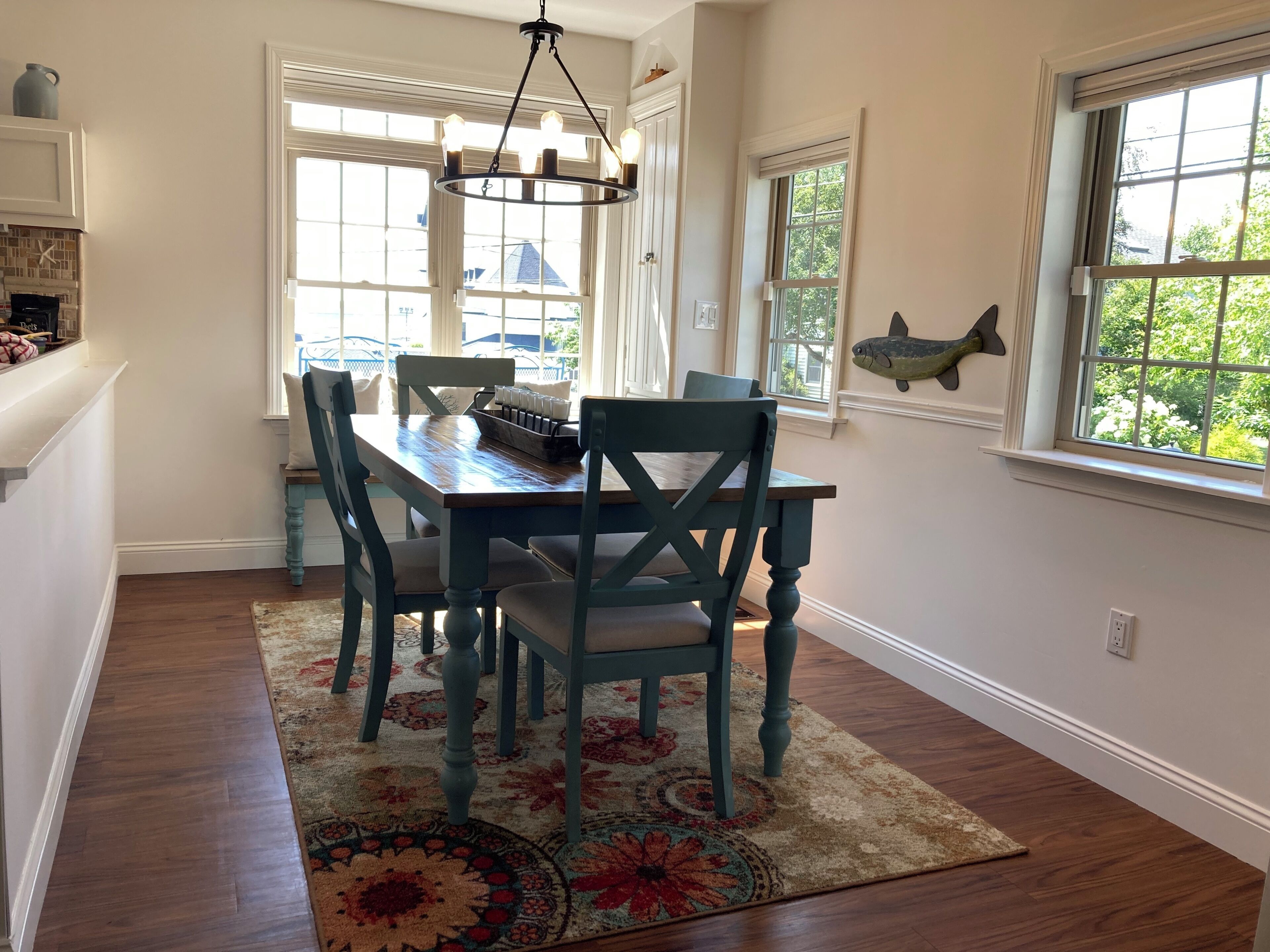 A dining area with a wooden table and chairs, a chandelier, and a fish decoration on the wall.