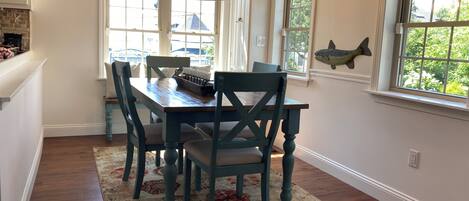 A dining area with a wooden table and chairs, a chandelier, and a fish decoration on the wall.