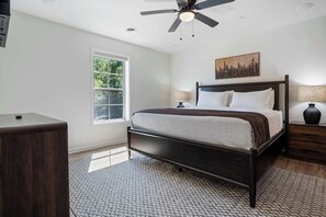 Quarto com cama, ventilador de teto, janela e mesa de cabeceira.