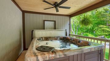 A hot tub with a wooden exterior, a ceiling fan, and a door in the background.