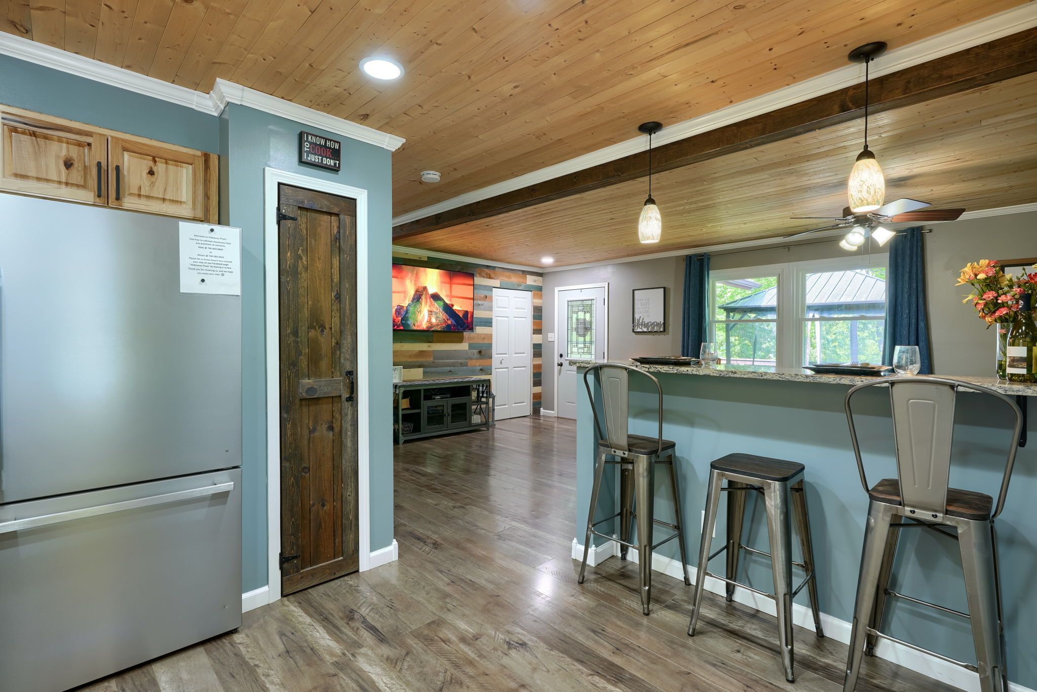 A kitchen with wooden cabinets, a refrigerator, a bar area with stools, and a dining table.
