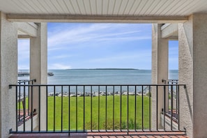 A covered outdoor area with a view of a body of water and a distant island. - Isle Be Back, Oceanfront Escape sleeps 4 (St Simons Island)