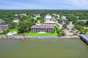 A hotel with a swimming pool, a parking lot, and a view of the surrounding area. - Isle Be Back, Oceanfront Escape sleeps 4 (St Simons Island)