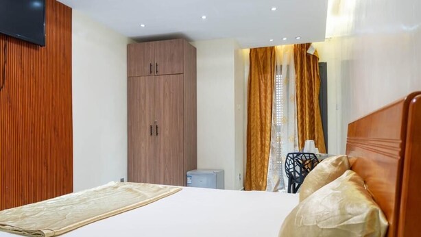 Hotelkamer met een bed, een aan de muur bevestigde televisie, een kledingkast en een bureau met stoel.