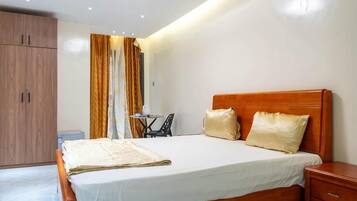 Une chambre à coucher avec un lit en bois, une table de chevet, une petite table avec une chaise et une armoire.
