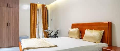 A bedroom with a wooden bed, a bedside table, a small table with a chair, and a wardrobe.