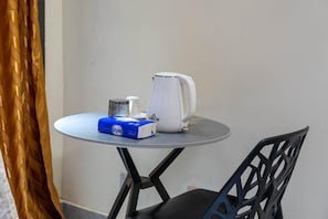 A small round table with a white kettle, a blue box labeled 'style,' and a metal container. - chambre c1 (Dakar)