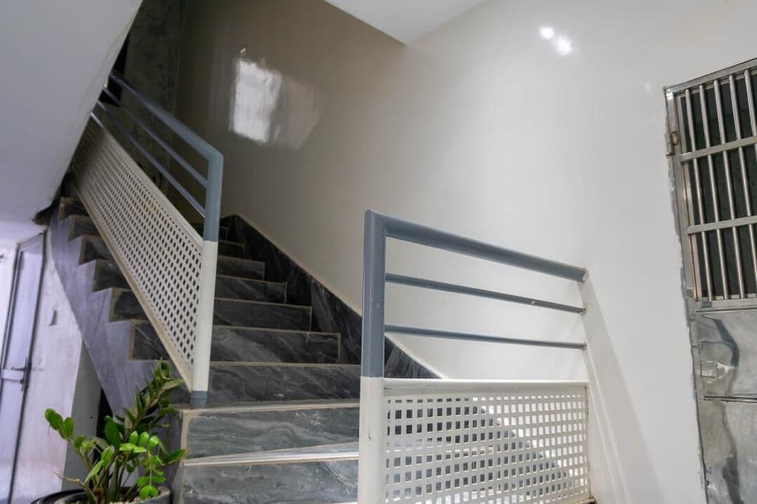 Un escalier doté d’une rampe métallique et d’une barrière de sécurité blanche en bas.