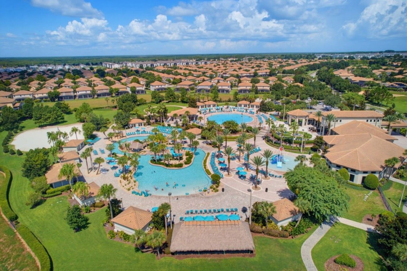 A resort with a central pool, multiple guest rooms, and a surrounding landscape.