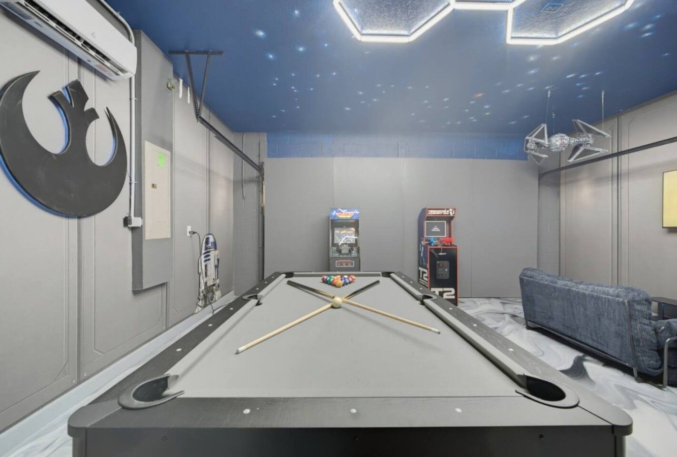 Una mesa de billar en una sala temática de Star Wars, con una gran luna creciente y decoración de R2-D2.