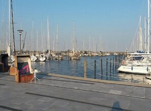 Un port de plaisance où sont amarrés de nombreux voiliers, un petit kiosque et un ciel dégagé.