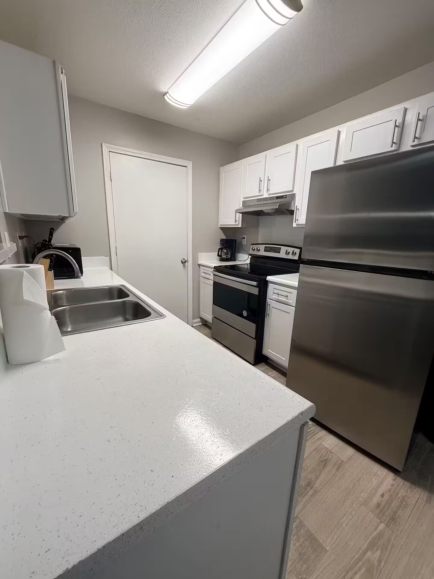 A modern kitchen with white cabinetry, stainless steel appliances, and a light-colored countertop.