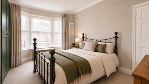 A bedroom with a bed, a nightstand, a lamp, and a window with curtains. - Smart 3 Bed House, Minutes From Penny Lane (Liverpool)