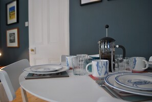 A dining table set with plates, glasses, and a coffee pot. - Crowstep Cottage- Character Crail apartment (Crail)