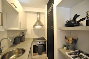 A compact kitchen with a stainless steel sink, a small oven, and a blackboard with writing. - Crowstep Cottage- Character Crail apartment (Crail)