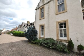 A traditional building with multiple windows and a gravel driveway. - Crowstep Cottage- Character Crail apartment (Crail)