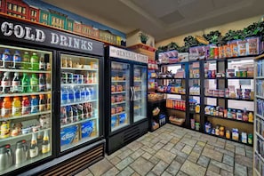 Una tienda de conveniencia con secciones refrigeradas para bebidas frías y una zona de tienda general con aperitivos y bebidas.
