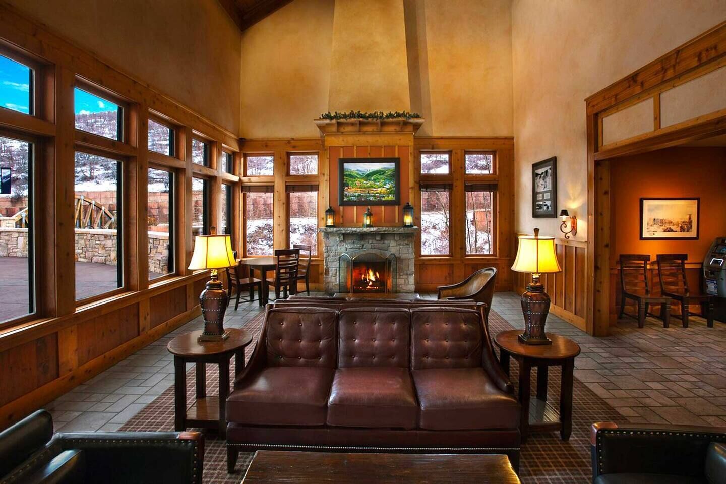 A cozy interior with a fireplace, leather sofa, and wooden walls.