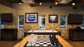 A room with a checkered chessboard, a billiards table, and framed pictures on the walls.
