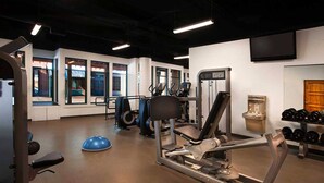 A gym with exercise equipment, a wall-mounted TV, and a window with a view of the outside. - Marriott's Summit Watch (Park City)