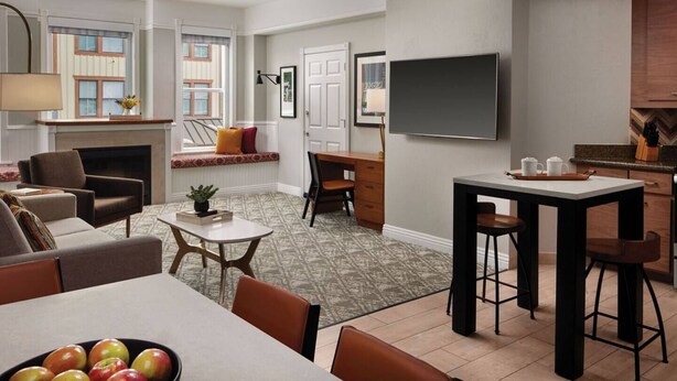 A modern living room with a fireplace, seating area, and a dining table with apples. - Marriott's Summit Watch (Park City)