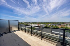 Ein Balkon mit Blick auf eine Stadtlandschaft, darunter Gebäude und ein klarer Himmel.