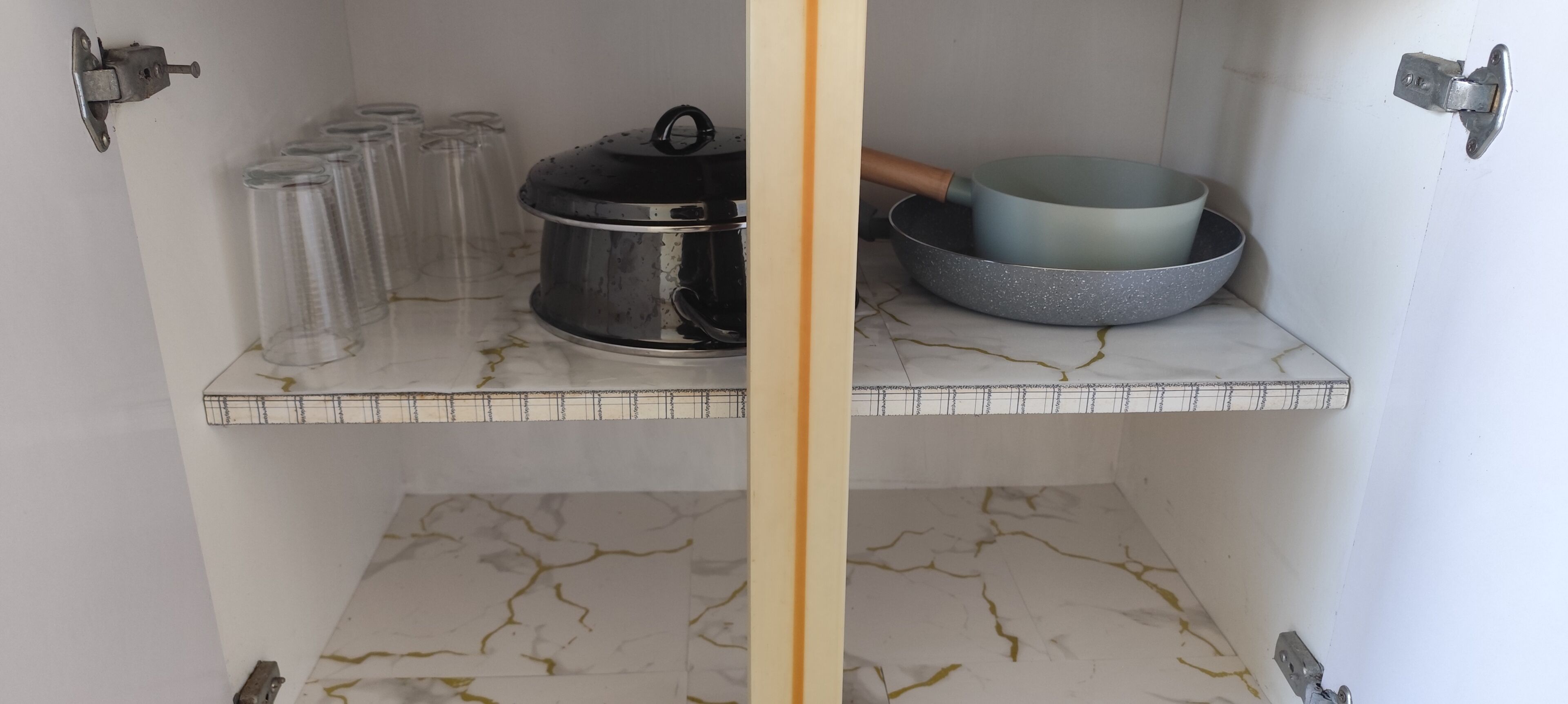A kitchen with a marble countertop, a pot, a bowl, and several glass containers.