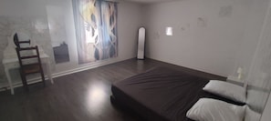 A bedroom with a bed, a chair, a mirror, and a window with a view. - Spacious House in the Peaceful Countryside (Val-Sonnette)