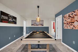 Et billardbord i et rum med grå vægge, en loftlampe og et skilt på væggen.