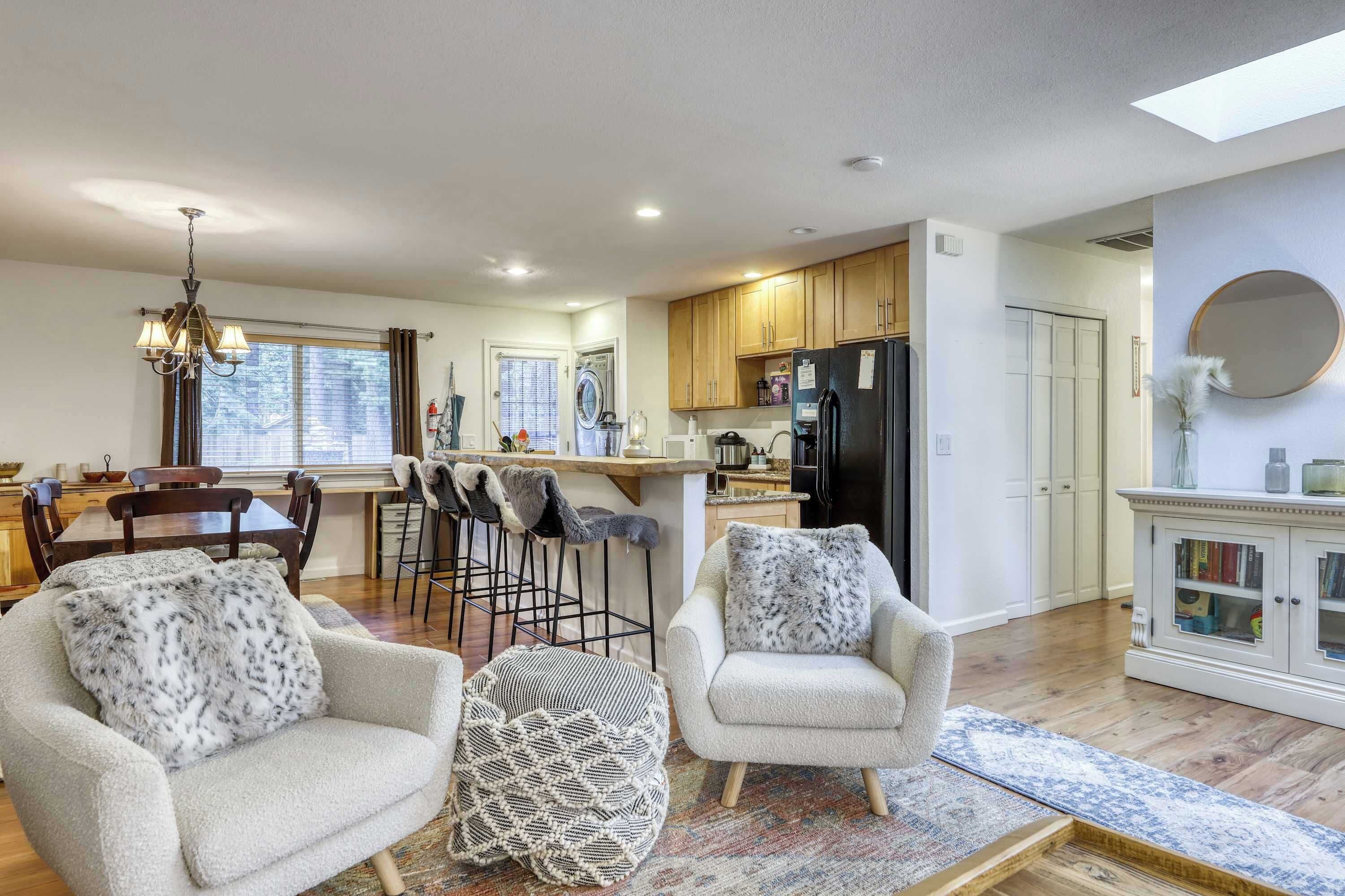A modern kitchen with a central island, wooden cabinets, and a black refrigerator.