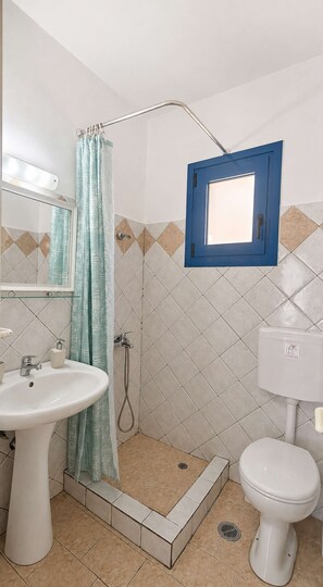 A bathroom with a shower, a sink, a toilet, and a mirror. - Sea View Studios in Syros – Litus Studios (Syros)