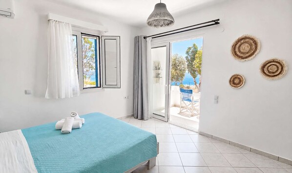 A bedroom with a bed, a window with curtains, a ceiling light, and a view of the outdoors. - Sea View Studios in Syros – Litus Studios (Syros)