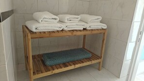 Een houten plank met witte handdoeken en een blauwe badmat in een badkamer.