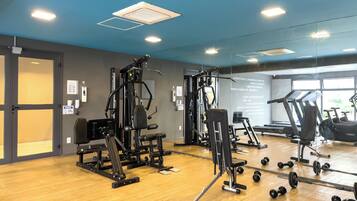 A gym with exercise equipment, a wooden floor, and a large window.