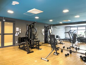 Une salle de sport équipée de matériel d’exercice, dotée d’un plancher en bois et d’une grande fenêtre.