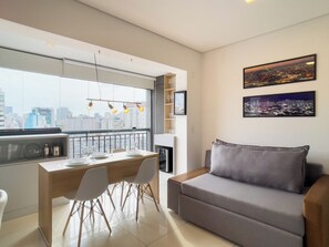 Un salon moderne avec un canapé, une table à manger, des chaises et une vue sur la ville grâce à de grandes fenêtres.