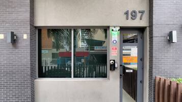 A building entrance with a glass door, a number '197' above it, and a sign indicating visitor entry.