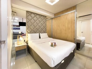 A modern hotel room with a large bed, a bedside table with a lamp, a wardrobe, and a mirror. - Genebra (São Paulo)