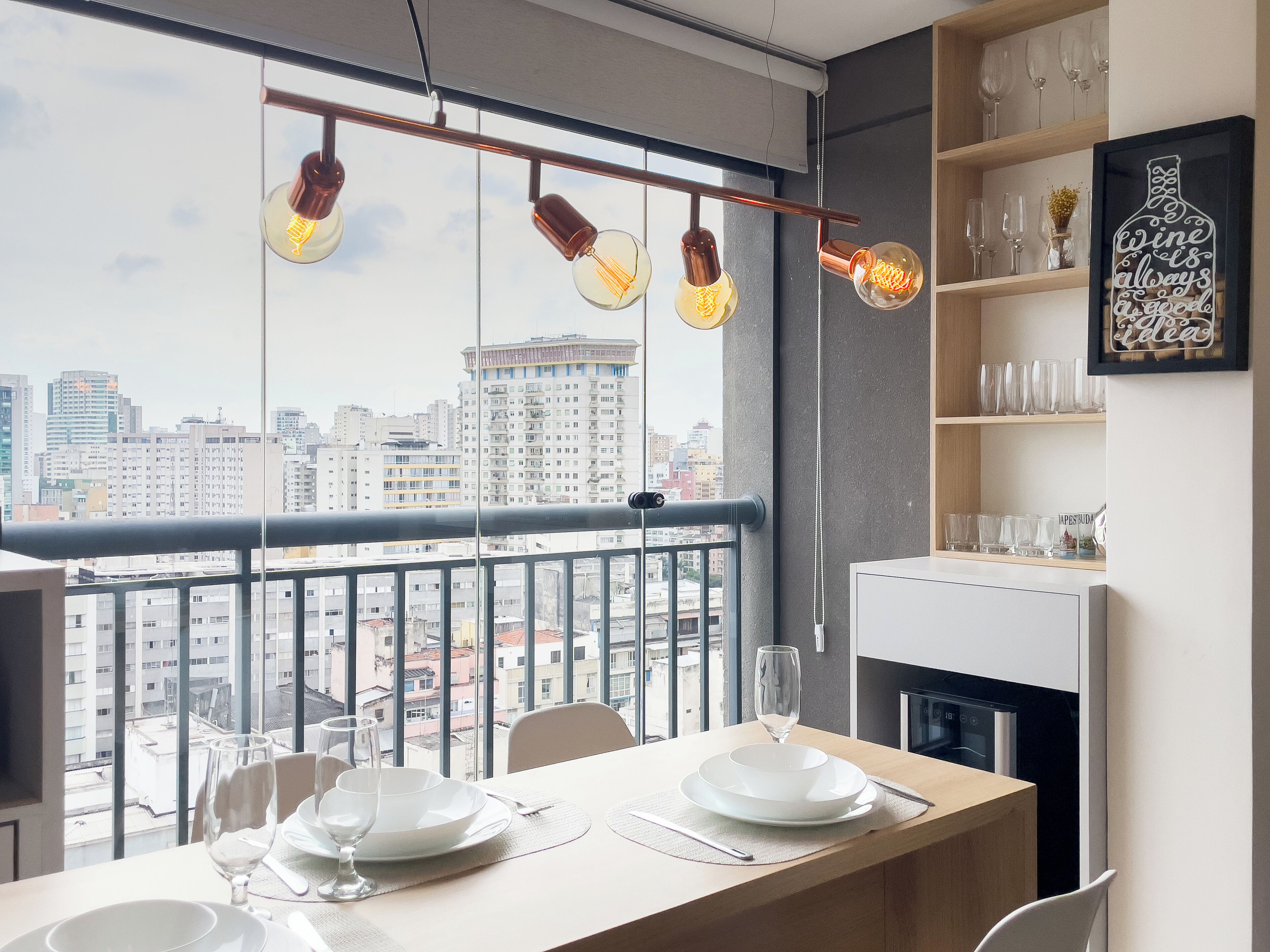 A dining area with a view of the cityscape, a modern kitchen, and a decorative wine bottle sign.