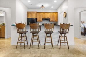 A kitchen with wooden cabinets, a black refrigerator, and a dining area with four wooden chairs. - ‘Reel’ Relaxing Luxury Retreat on Pike Lake (Duluth)