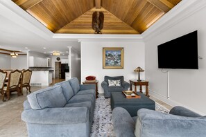 Un salon moderne avec un canapé d’angle, une table basse et un téléviseur à écran plat fixé au mur.
