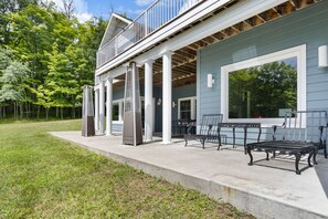 A two-story building with a covered patio area, outdoor seating, and a view of the surrounding trees. - ‘Reel’ Relaxing Luxury Retreat on Pike Lake (Duluth)