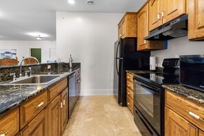 A kitchen with wooden cabinets, a stainless steel refrigerator, and a black stove. - ‘Reel’ Relaxing Luxury Retreat on Pike Lake (Duluth)