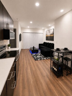 A modern kitchen with a dining area, a black sofa, and a wine rack. - Stylish 1-bedroom in Midtown Atlanta-Across From Mercedes Benz Stadium (Atlanta)